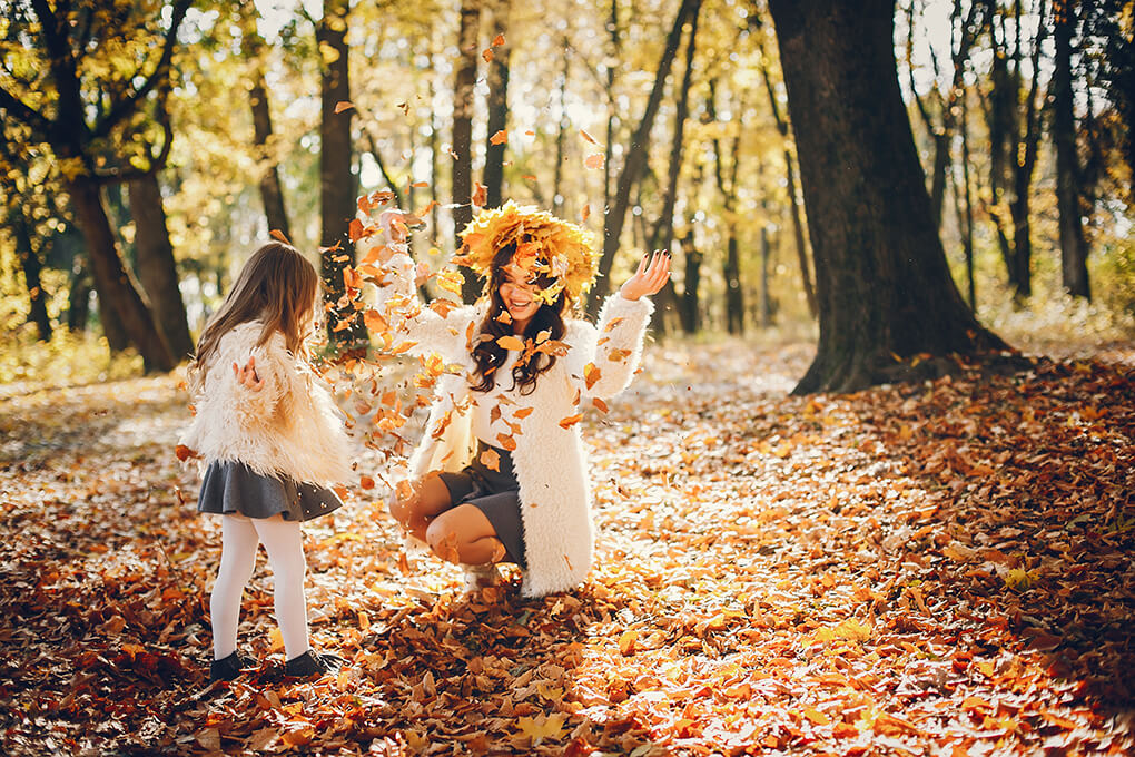 Madre e hija jugando en un bosque en otoño